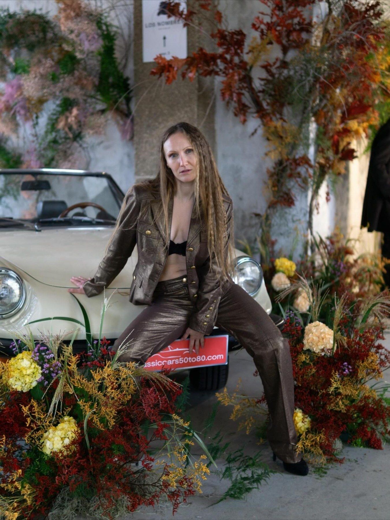 Modelo posando junto al coche clásico decorado con flores