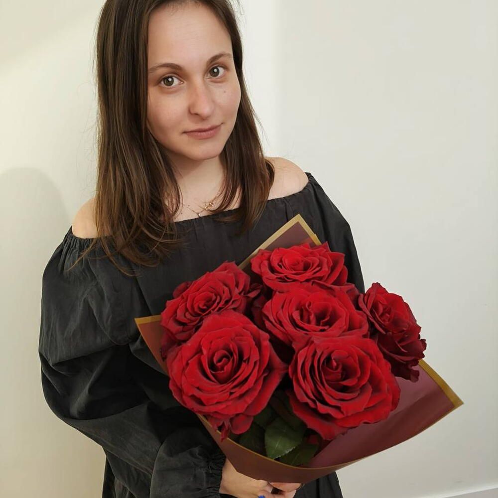 La florista de My Agosto sujetando un ramo de rosas rojas
