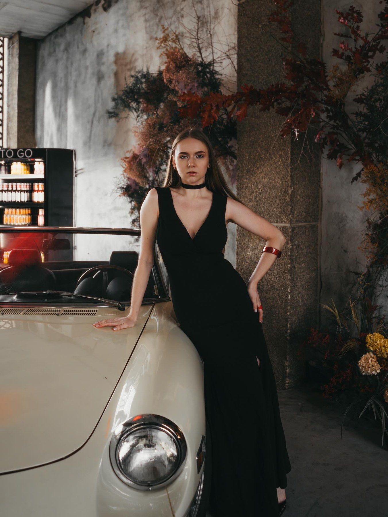 Modelo con vestido negro junto al coche clásico y la instalación floral